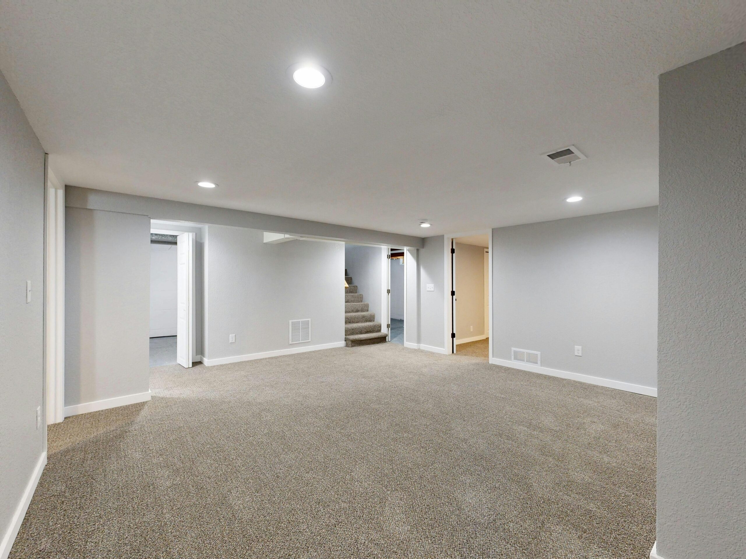 Spacious modern basement with neutral design and carpet flooring, perfect for renovation or real estate listings.